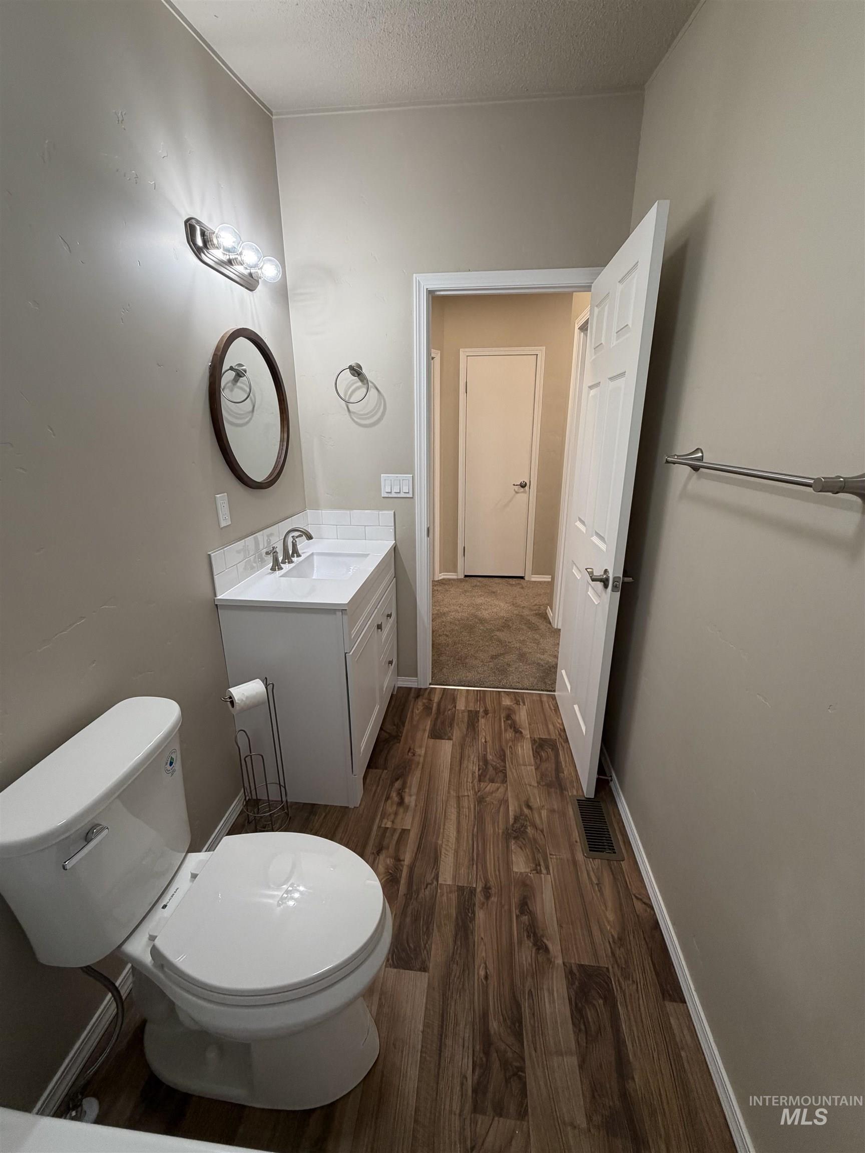 815 East Liberty Street Weiser, ID 83672 - Photo 18 of 25 Half bath with dark wood finished floors, vanity, and a textured ceiling