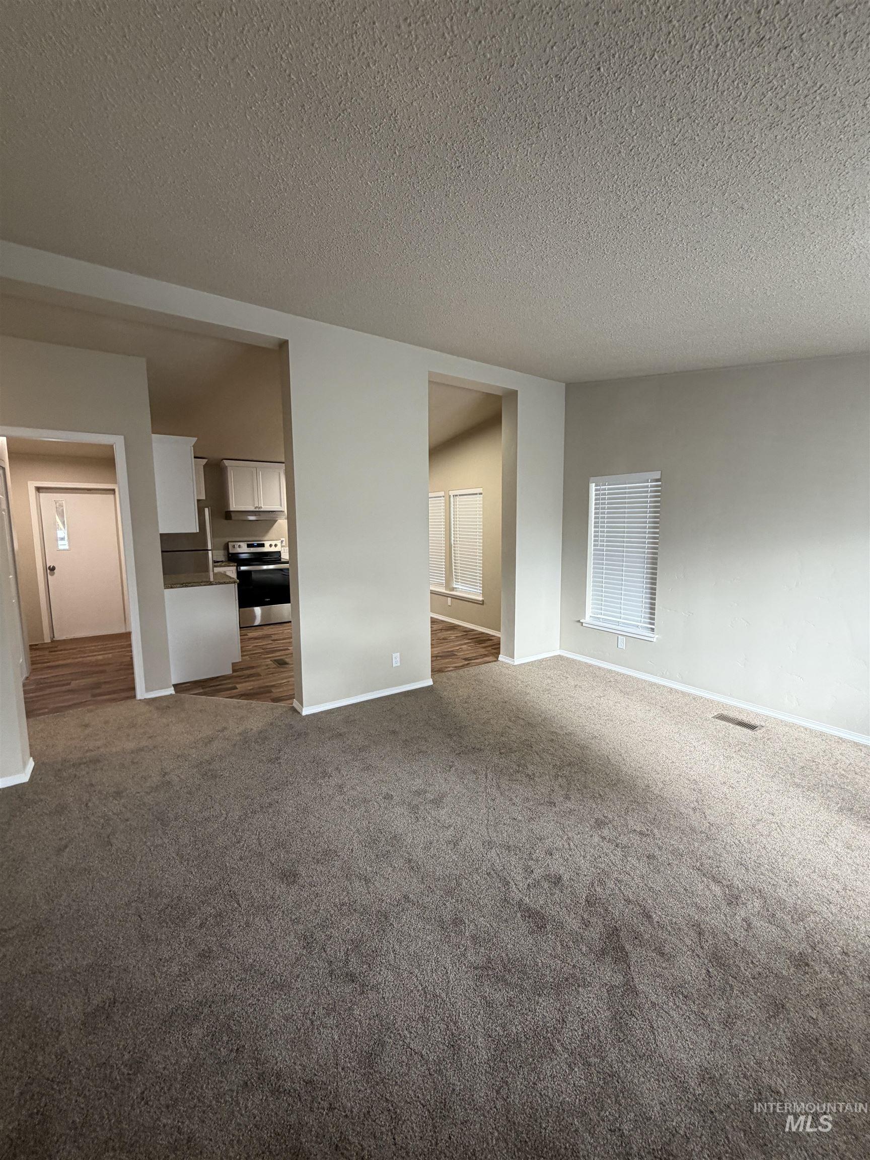 815 East Liberty Street Weiser, ID 83672 - Photo 3 of 25 Unfurnished living room featuring a textured ceiling and dark colored carpet
