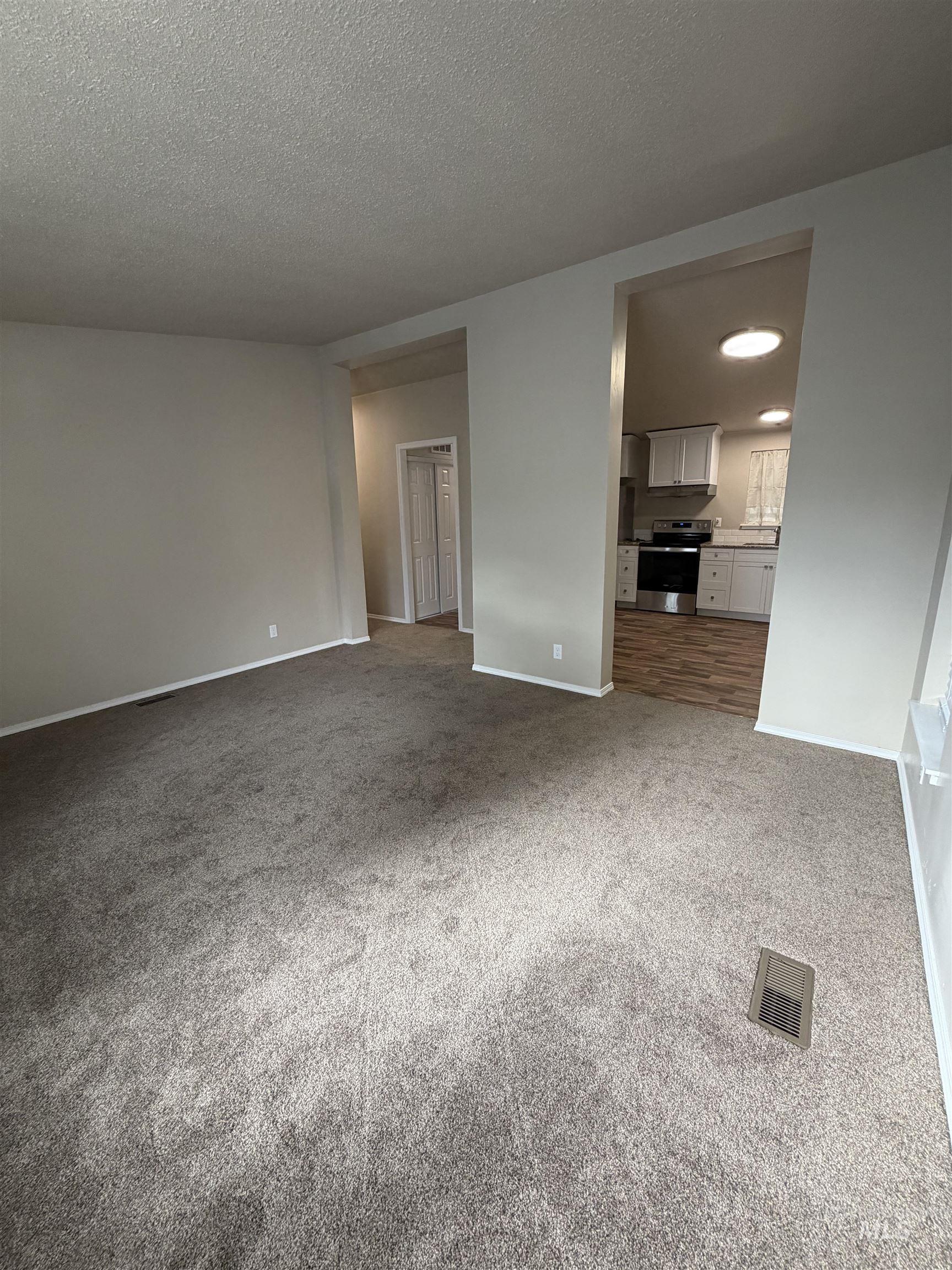815 East Liberty Street Weiser, ID 83672 - Photo 4 of 25 Unfurnished living room with light carpet and a textured ceiling