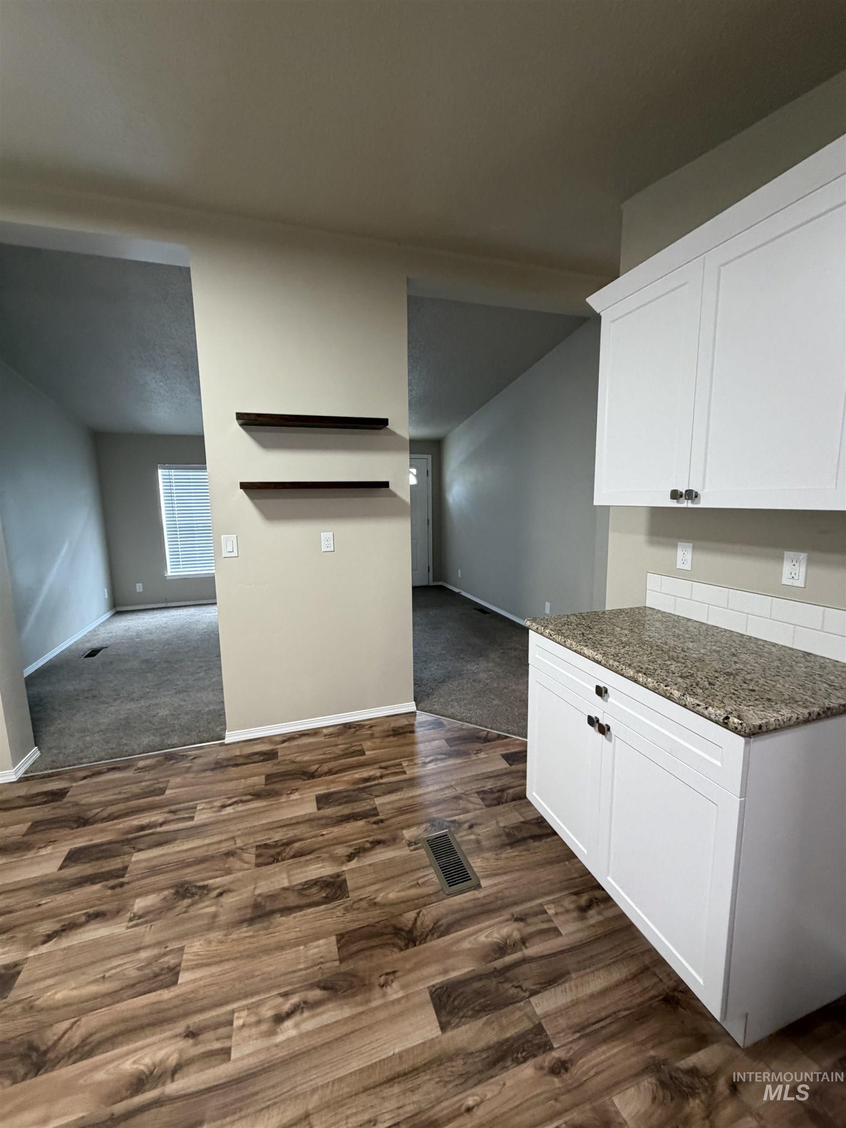 815 East Liberty Street Weiser, ID 83672 - Photo 25 of 25 Kitchen featuring dark stone countertops, white cabinets, dark wood-style flooring, dark colored carpet, and open floor plan
