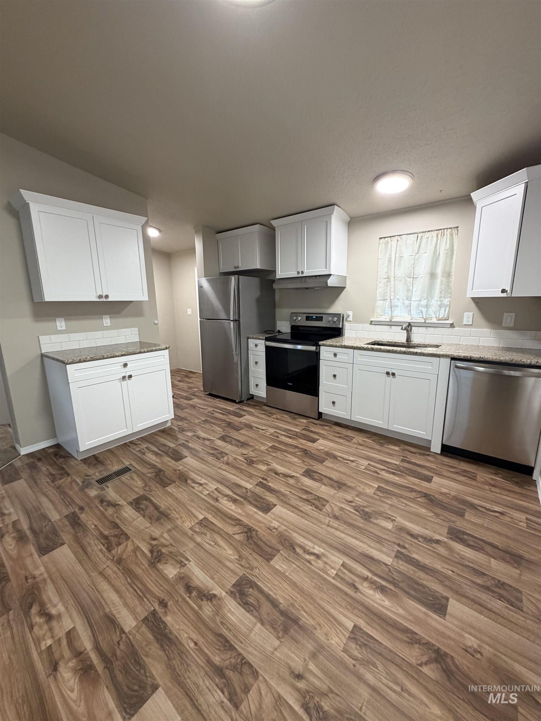 815 East Liberty Street Weiser, ID 83672 - Photo 6 of 25 Kitchen featuring stainless steel appliances, white cabinetry, dark wood-style flooring, and light stone countertops