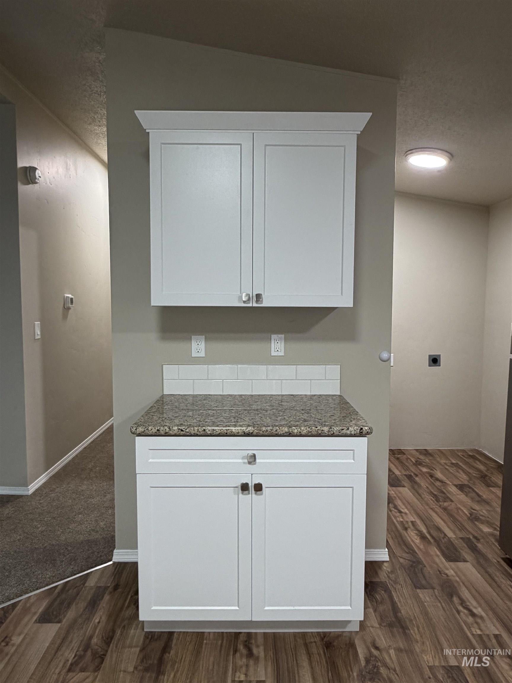 815 East Liberty Street Weiser, ID 83672 - Photo 9 of 25 Kitchen featuring dark stone counters, dark wood-style floors, white cabinets, and a textured ceiling
