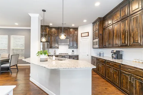 a large kitchen with kitchen island granite countertop a stove a sink a center island and couches