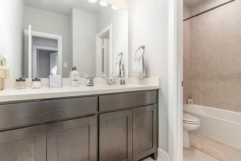a bathroom with a double vanity sink toilet mirror and bathtub