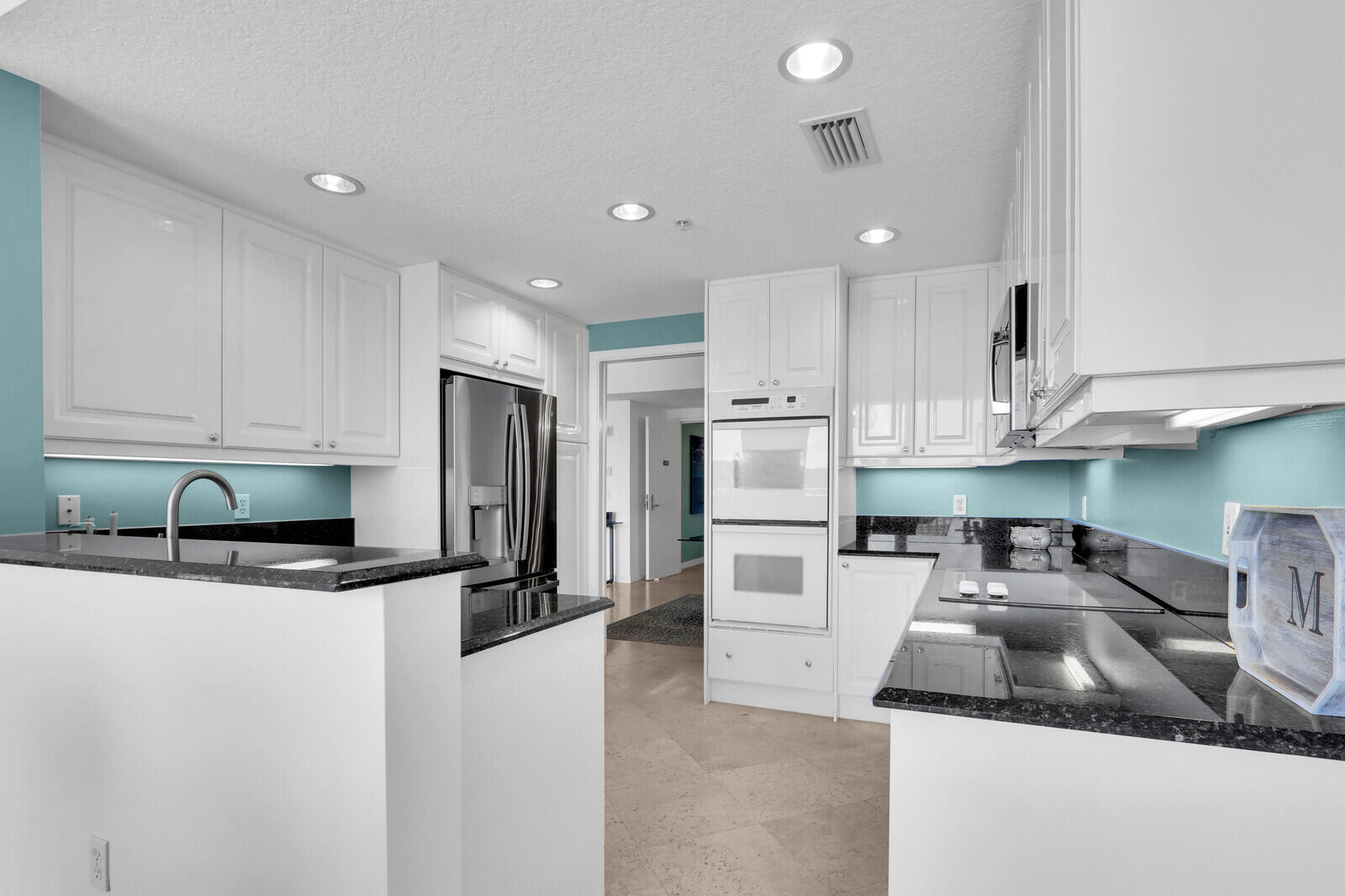 700 Ocean Royale, Unit 202 Juno Beach, FL 33408 - Photo 9 of 34 a kitchen with stainless steel appliances granite countertop a sink refrigerator and cabinets