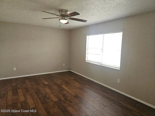 a view of a small space with wooden floor and a fan