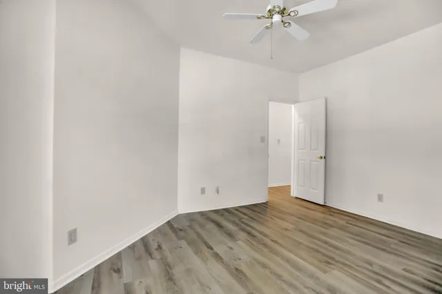 an empty room with a ceiling fan and wooden floor
