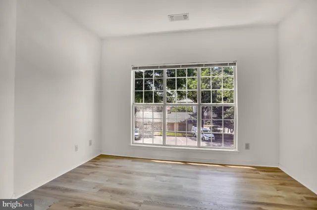 an empty room with wooden floor and windows