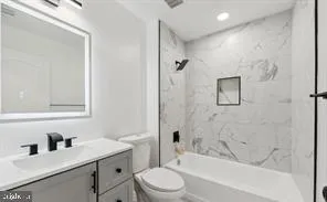 a bathroom with a bathtub shower sink vanity mirror and toilet