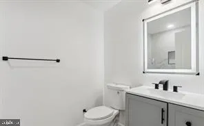 a bathroom with a granite countertop sink vanity mirror and toilet