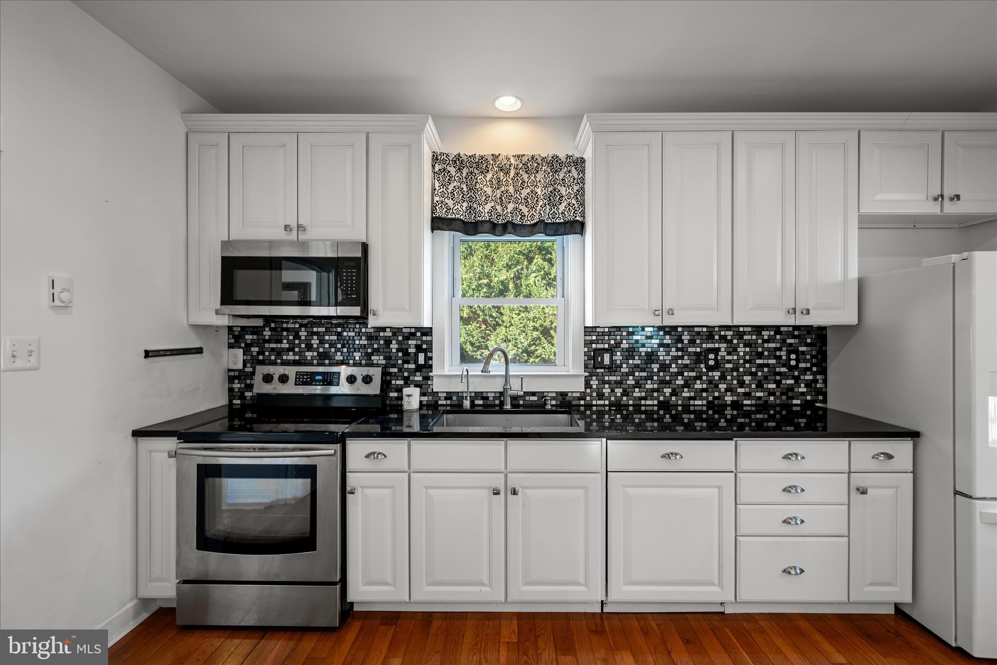 129 Church Street Summit Point, WV 25446 - Photo 45 of 91 a kitchen with granite countertop a stove a microwave a sink and cabinets
