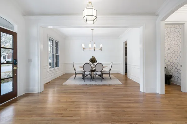 a dining room with wooden floor a chandelier a glass table and chairs