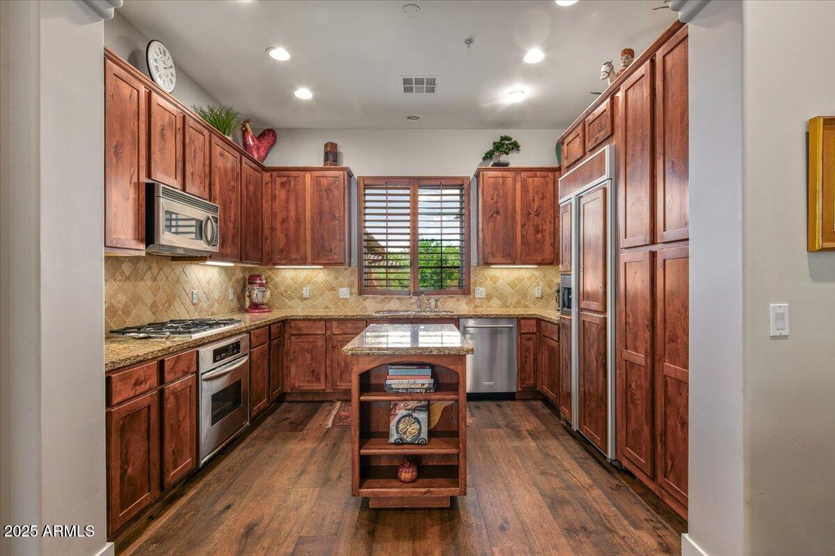 20704 North 90th Place, Unit 1004 Scottsdale, AZ 85255 - Photo 13 of 28 a kitchen with granite countertop wooden floors wooden cabinets and stainless steel appliances