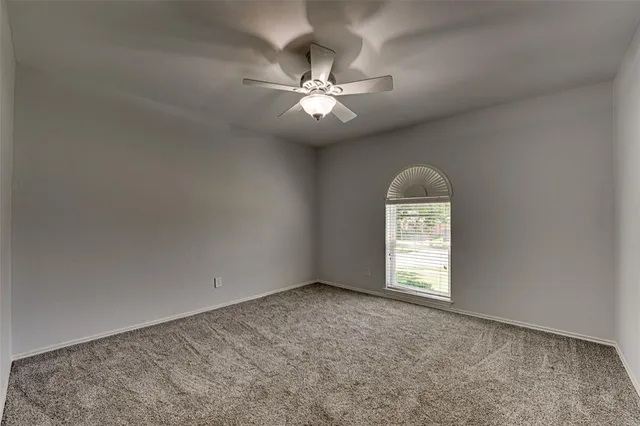 en empty room with windows and ceiling fan