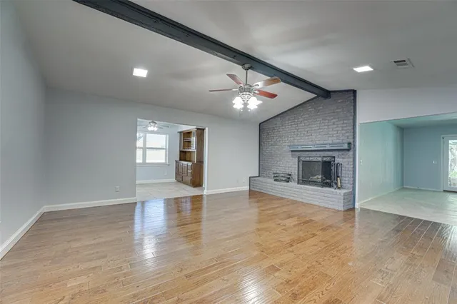an empty room with wooden floor fireplace and windows