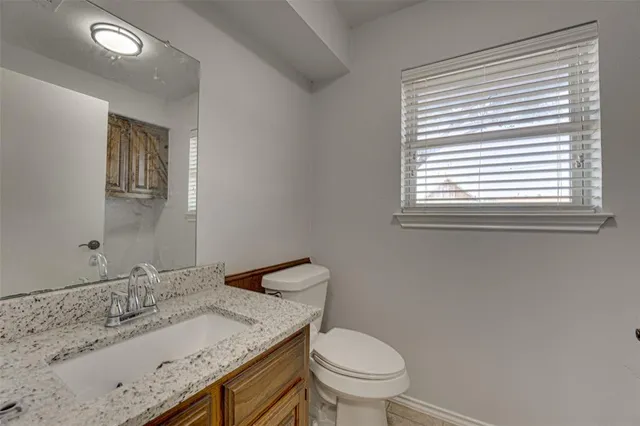 a bathroom with a granite countertop sink toilet and a mirror