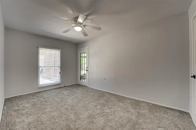 an empty room with chandelier fan and windows