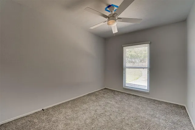 an empty room with a chandelier fan and windows