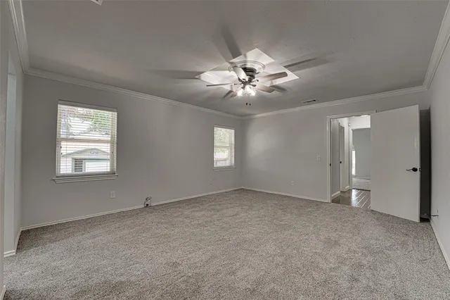 an empty room with chandelier fan and windows