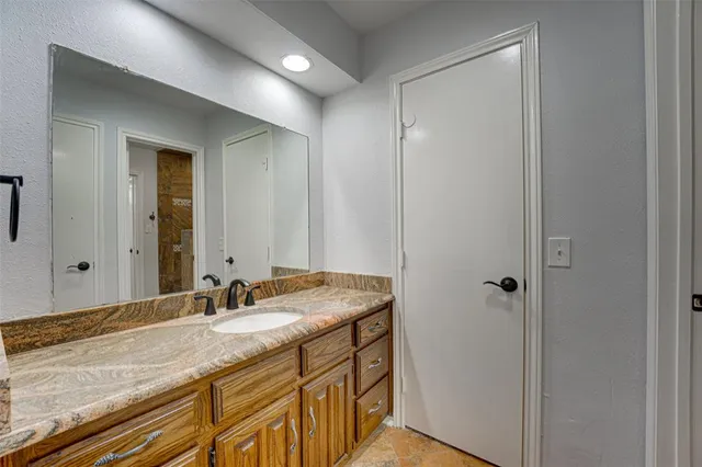 a bathroom with a granite countertop sink and a mirror