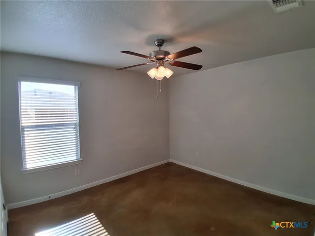 an empty room with windows and fan