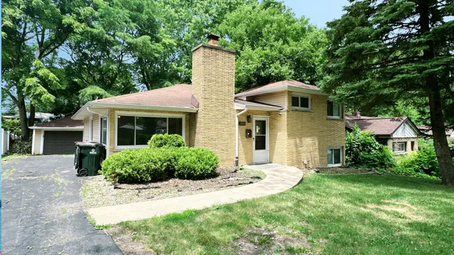 a front view of a house with a yard and trees