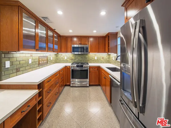 a large kitchen with stainless steel appliances granite countertop lots of counter top space and wooden floor