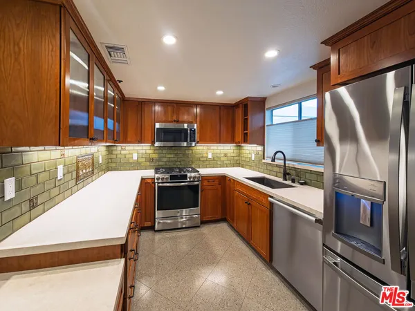 a kitchen with stainless steel appliances granite countertop a refrigerator sink and stove