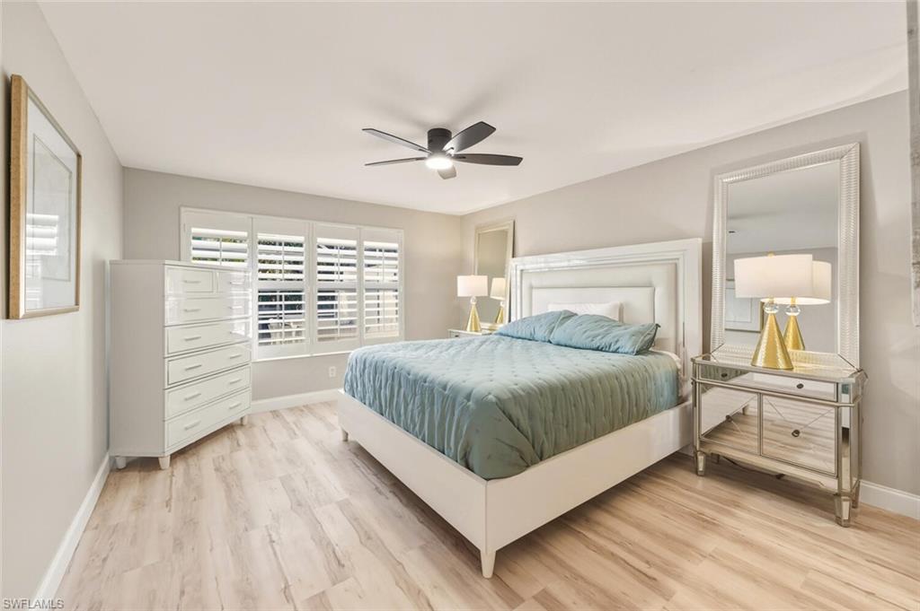 3408 Cayman Lane Naples, FL 34119 - Photo 15 of 34 a bedroom with a large bed a chandelier and windows