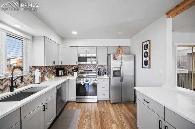 a kitchen with white cabinets stainless steel appliances and a window