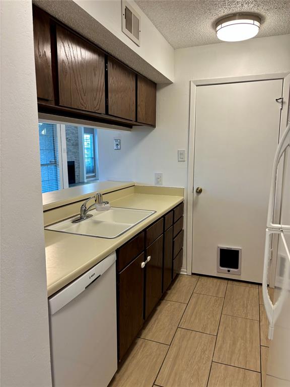12480 Abrams Road, Unit 2805 Dallas, TX 75243 - Photo 12 of 18 Kitchen with dark wood finish cabinetry, white appliances, light countertops, and a textured ceiling