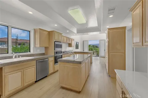 a kitchen with stainless steel appliances granite countertop a refrigerator a sink dishwasher a oven and a dining table with wooden floor