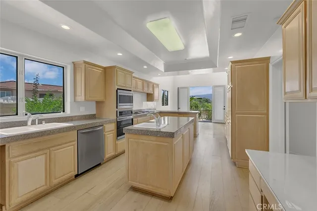 a kitchen with stainless steel appliances granite countertop a refrigerator a sink dishwasher a oven and a dining table with wooden floor