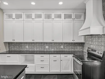 a kitchen with granite countertop white cabinets and stainless steel appliances