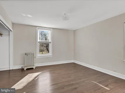 a view of an empty room with wooden floor and closet