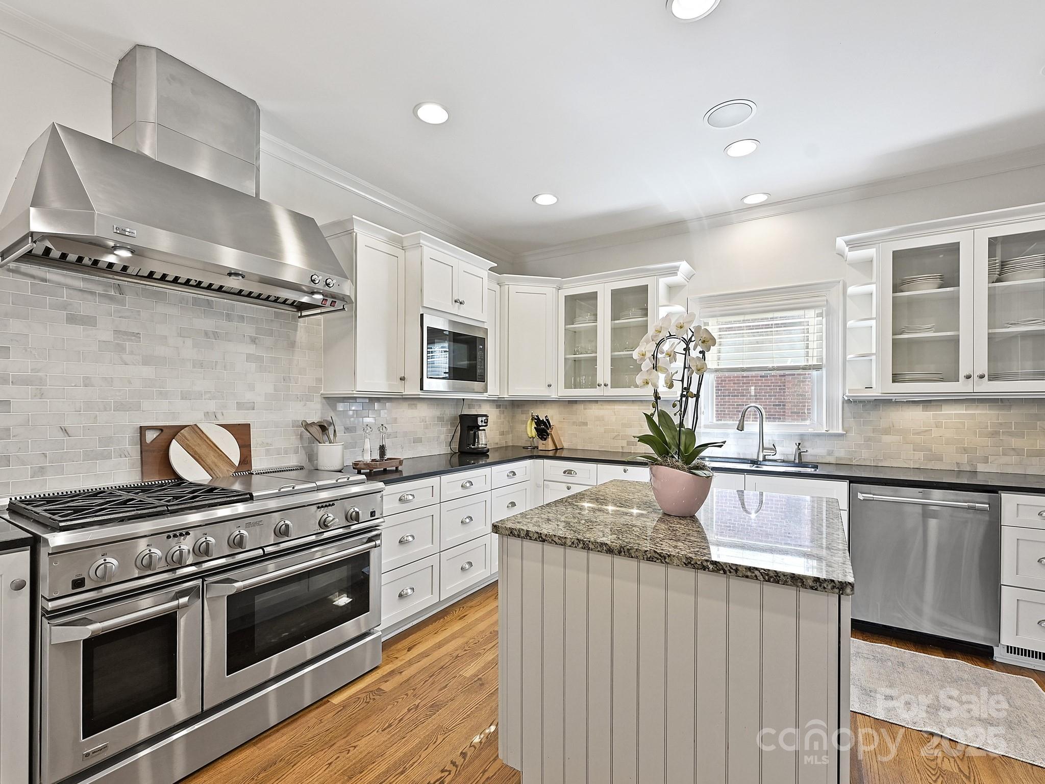 3915 Ayscough Road Charlotte, NC 28211 - Photo 12 of 45 a kitchen with stainless steel appliances granite countertop a stove a sink dishwasher and white cabinets with wooden floor