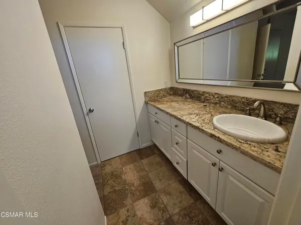 a bathroom with a granite countertop sink and a mirror
