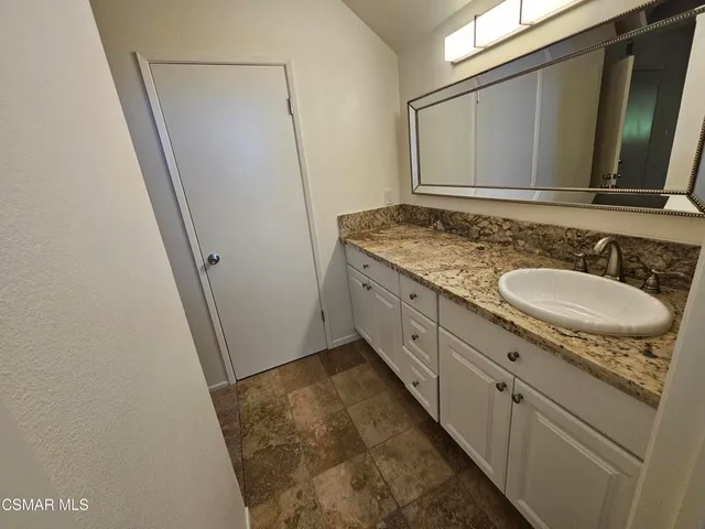 a bathroom with a granite countertop sink and a mirror