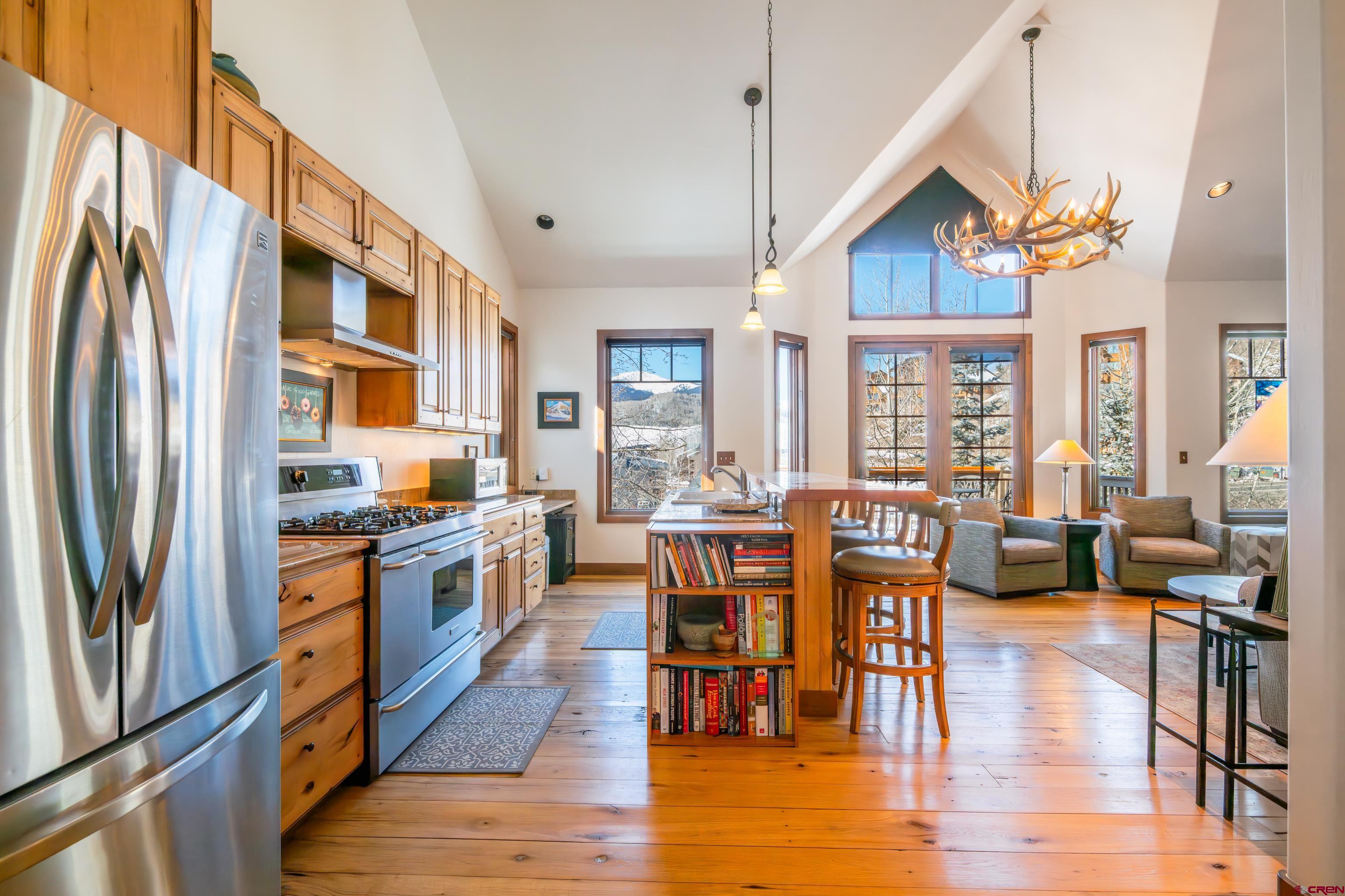 11 Castle Road Crested Butte, CO 81225 - Photo 3 of 45 a kitchen with stainless steel appliances granite countertop a stove top oven a refrigerator a dining table and chairs with wooden floor