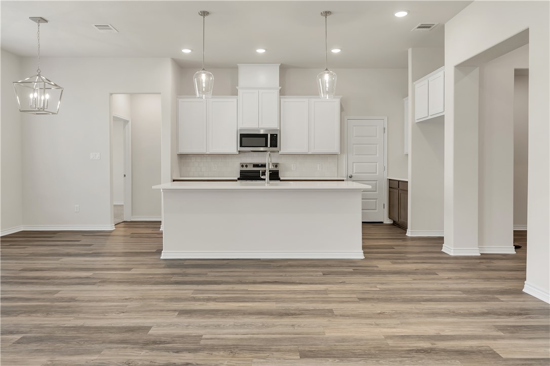 1931 Pinemont View Drive Bryan, TX 77807 - Photo 11 of 43 a view of kitchen with stainless steel appliances granite countertop a stove top oven a refrigerator white cabinets and couches with wooden floor