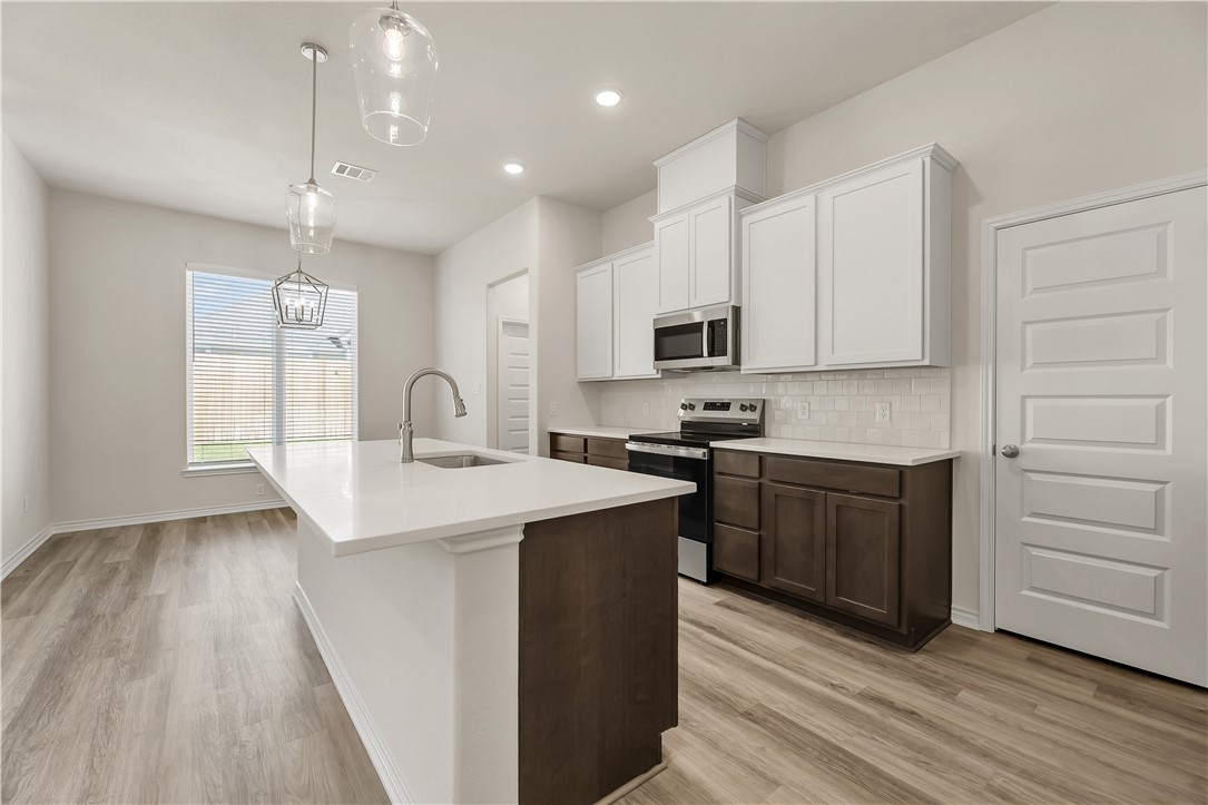 1931 Pinemont View Drive Bryan, TX 77807 - Photo 12 of 43 a kitchen with kitchen island granite countertop a sink cabinets and wooden floor