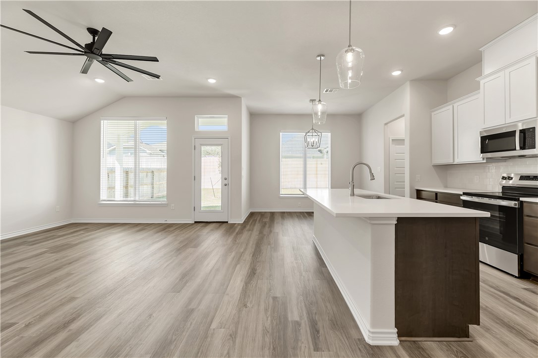 1931 Pinemont View Drive Bryan, TX 77807 - Photo 4 of 43 a kitchen with kitchen island white cabinets and black stainless steel appliances