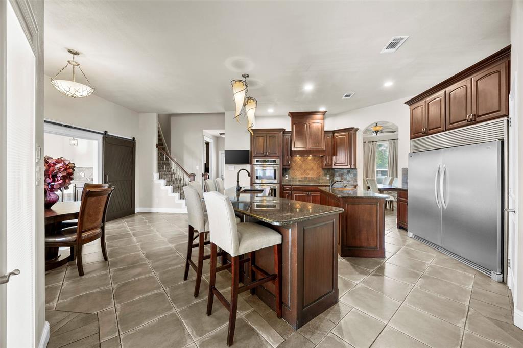 219 Mohundro Road Ferris, TX 75125 - Photo 8 of 40 a kitchen with stainless steel appliances kitchen island granite countertop a table chairs and a refrigerator