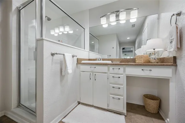a spacious bathroom with a granite countertop sink a mirror and a shower