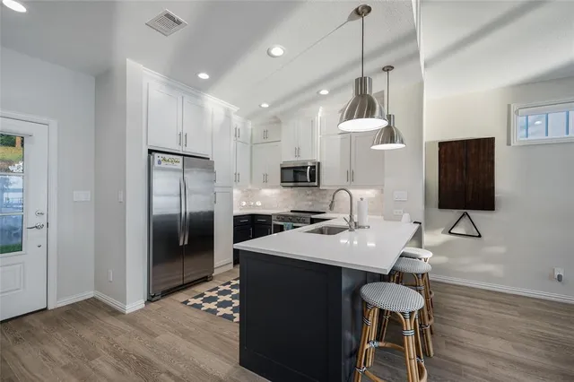 a kitchen with stainless steel appliances kitchen island granite countertop a sink a microwave a refrigerator and a stove