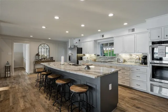 a kitchen with stainless steel appliances granite countertop a table chairs sink and cabinets