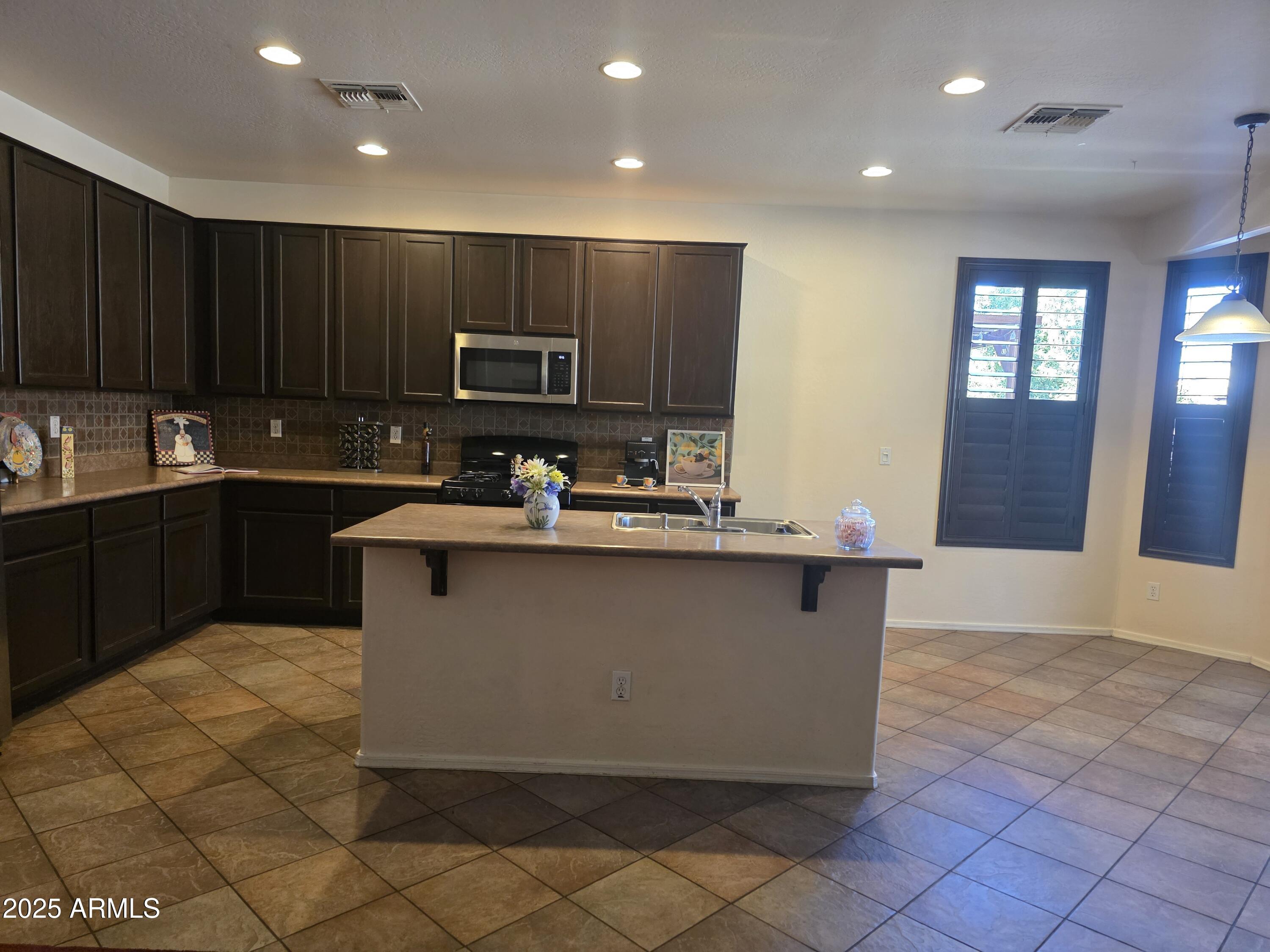 1162 East Springfield Place Chandler, AZ 85286 - Photo 8 of 27 a kitchen with kitchen island granite countertop a stove a sink and a refrigerator