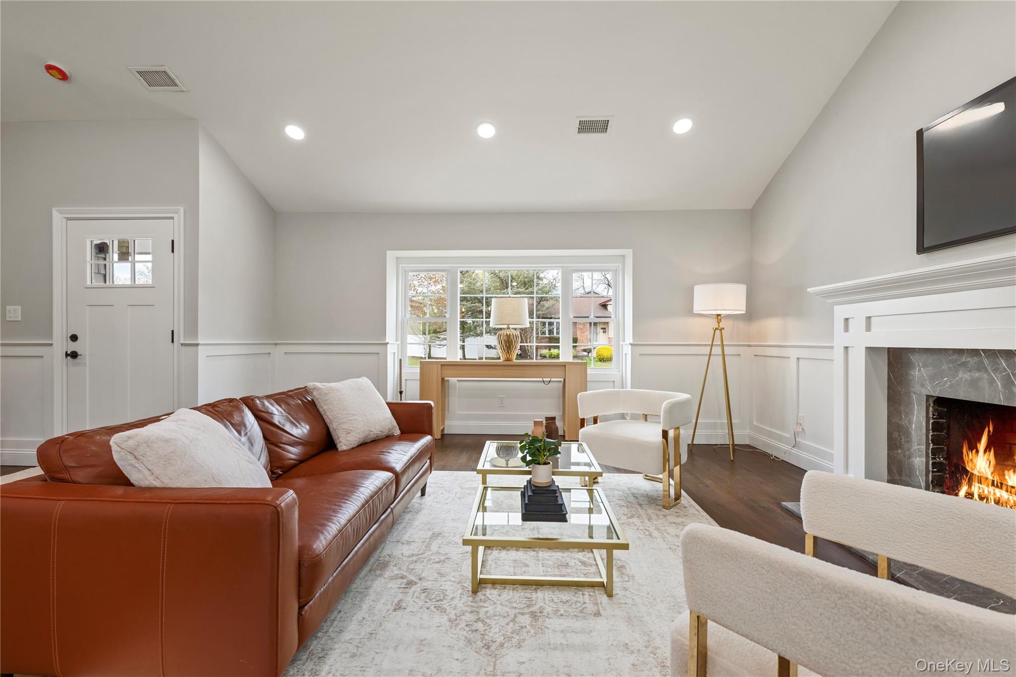 16 Eleanor Road Plainview, NY 11803 - Photo 5 of 28 Living area featuring a fireplace with a stone and white mantel, hard wood flooring, wainscoting, and recessed lighting