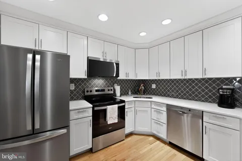 a kitchen with granite countertop a refrigerator and a stove top oven