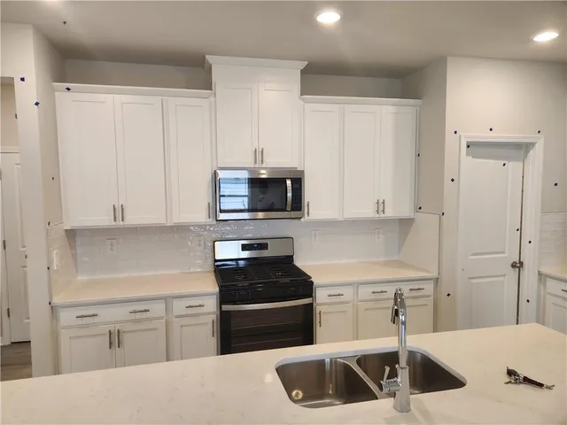 a kitchen with white cabinets and black appliances